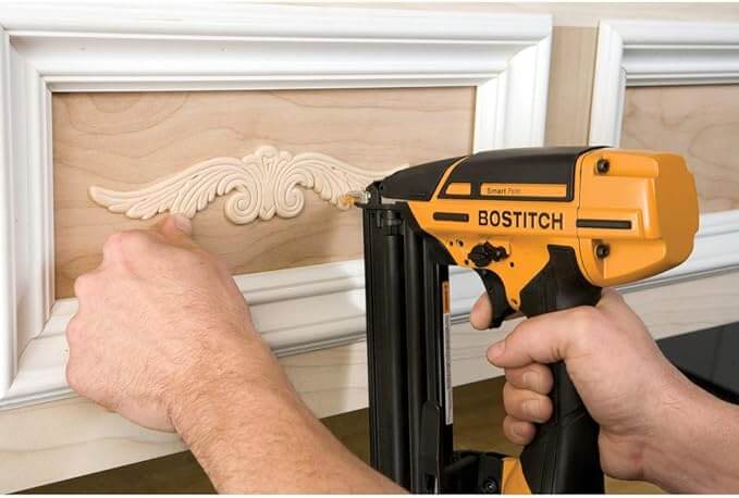 brad nailer being used on a baseboard